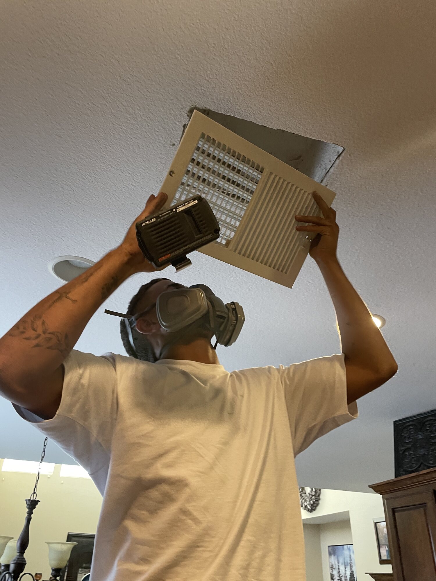 Technician removing a ceiling vent cover during an air duct service call